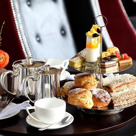 Macdonald Bath Spa Hotel Екстериор снимка The photo depicts an elegantly arranged afternoon tea setting. There is a tiered stand filled with a variety of treats, including scones, sandwiches, and small desserts like cakes and pastries. Accompanying this is a teapot and a cup on the table, su