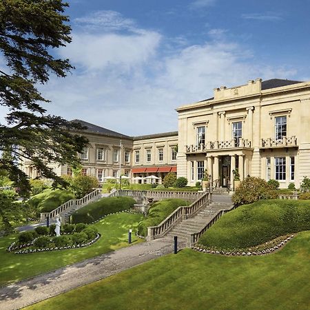 Macdonald Bath Spa Hotel Екстериор снимка The photo shows a grand building, likely a hotel or estate, surrounded by well-manicured gardens and lawns. The architecture appears elegant, with multiple stories and large windows. There are steps leading up to the entrance, and the setting include