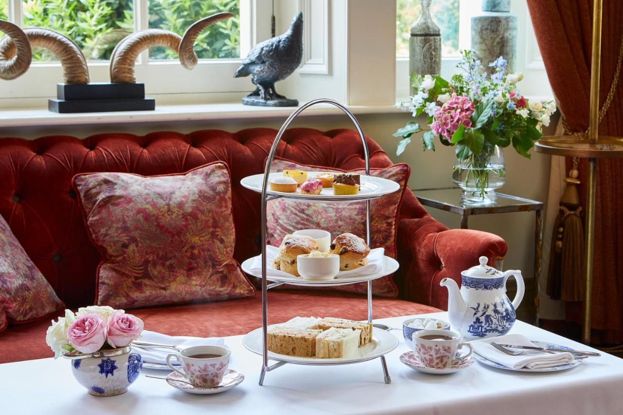 Macdonald Bath Spa Hotel Екстериор снимка The photo showcases an elegant afternoon tea setting. In the foreground, there is a three-tiered serving stand filled with various pastries and scones, including some topped with cream and fruit. Surrounding the stand is a beautifully arranged table 