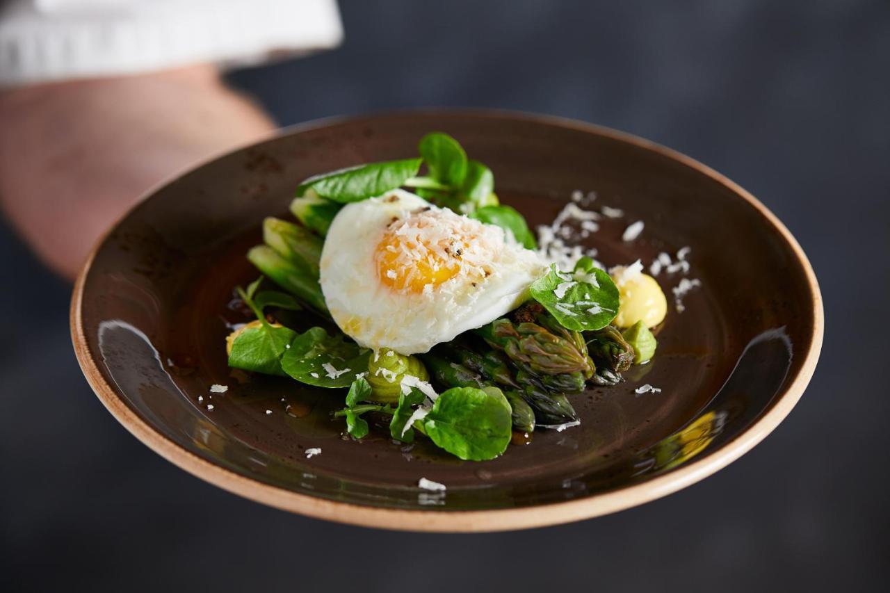 Macdonald Bath Spa Hotel Екстериор снимка The photo shows a plate of beautifully arranged food, featuring a poached egg on top of a mix of fresh greens. The greens include asparagus, lettuce, and possibly some herbs, garnished with a sprinkle of grated cheese or a similar topping. The dish i