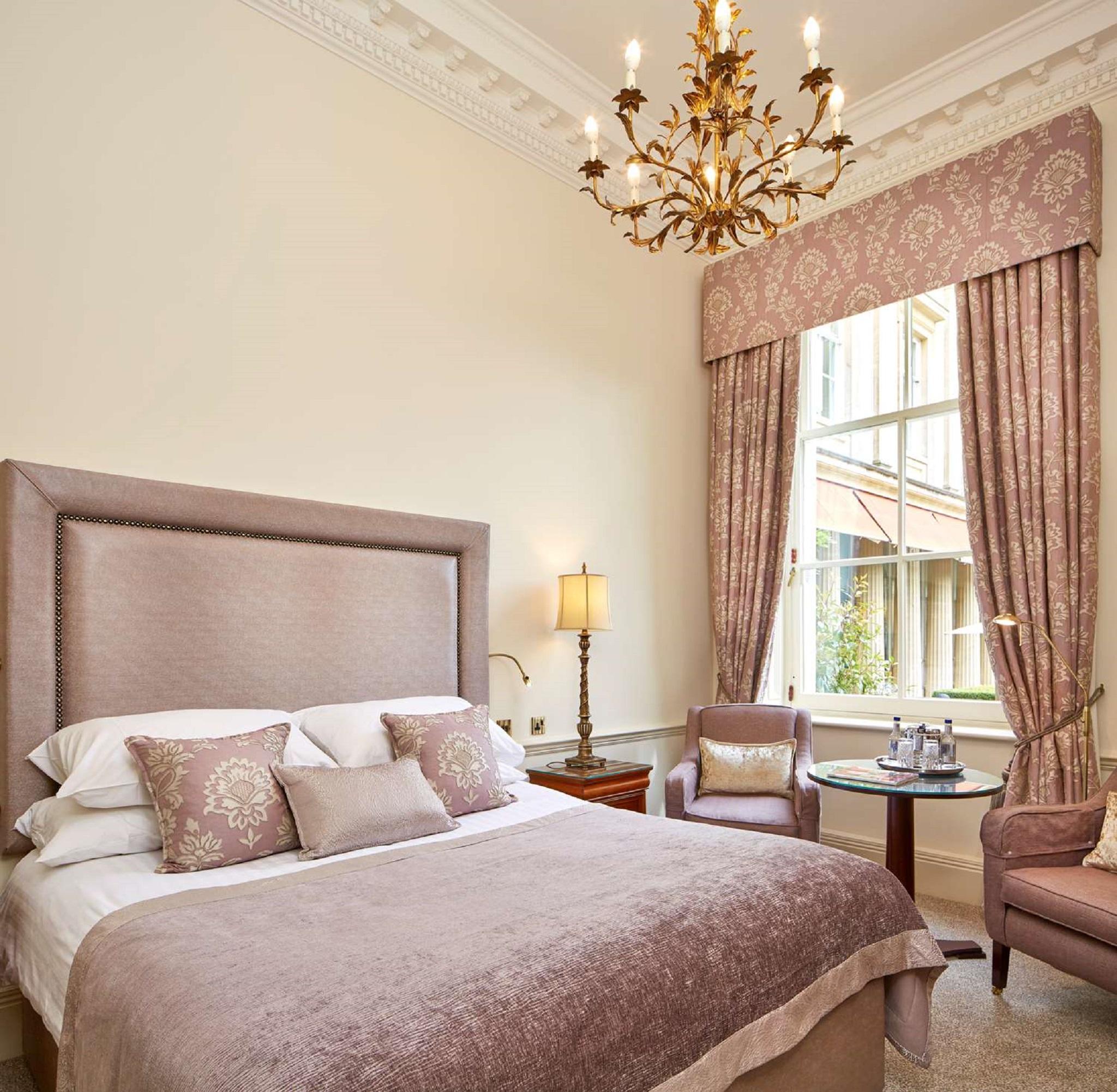 Macdonald Bath Spa Hotel Екстериор снимка The photo shows a beautifully decorated hotel room. It features a large bed with a plush headboard, adorned with several decorative pillows. The walls are painted in a soft color, and there is a chandelier hanging from the ceiling. Natural light come