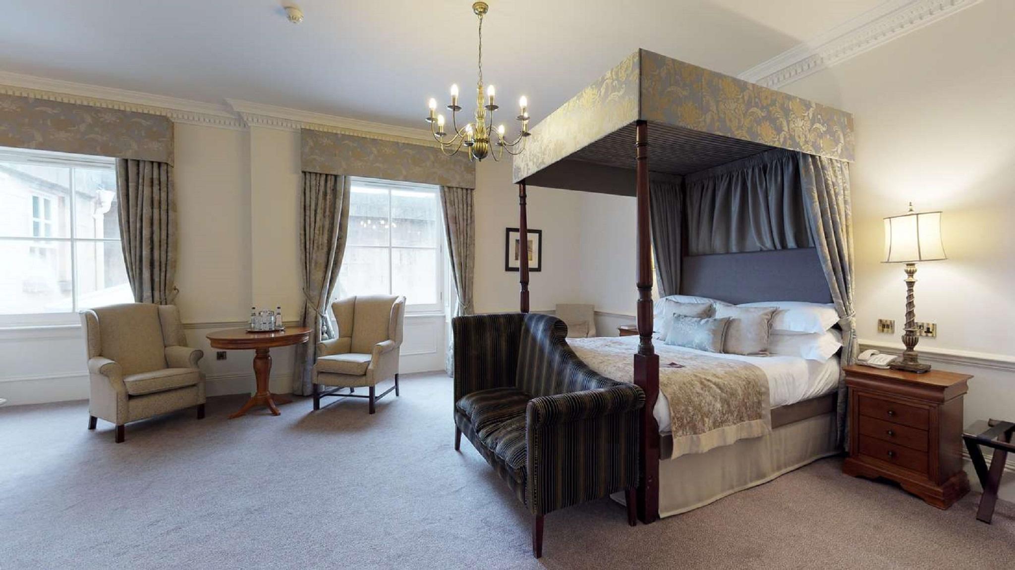 Macdonald Bath Spa Hotel Екстериор снимка The photo shows a stylish hotel room featuring a four-poster bed with a decorative canopy. The bed is positioned prominently in the center, surrounded by plush bedding. To the side, there are two armchairs with a small round table between them, creat