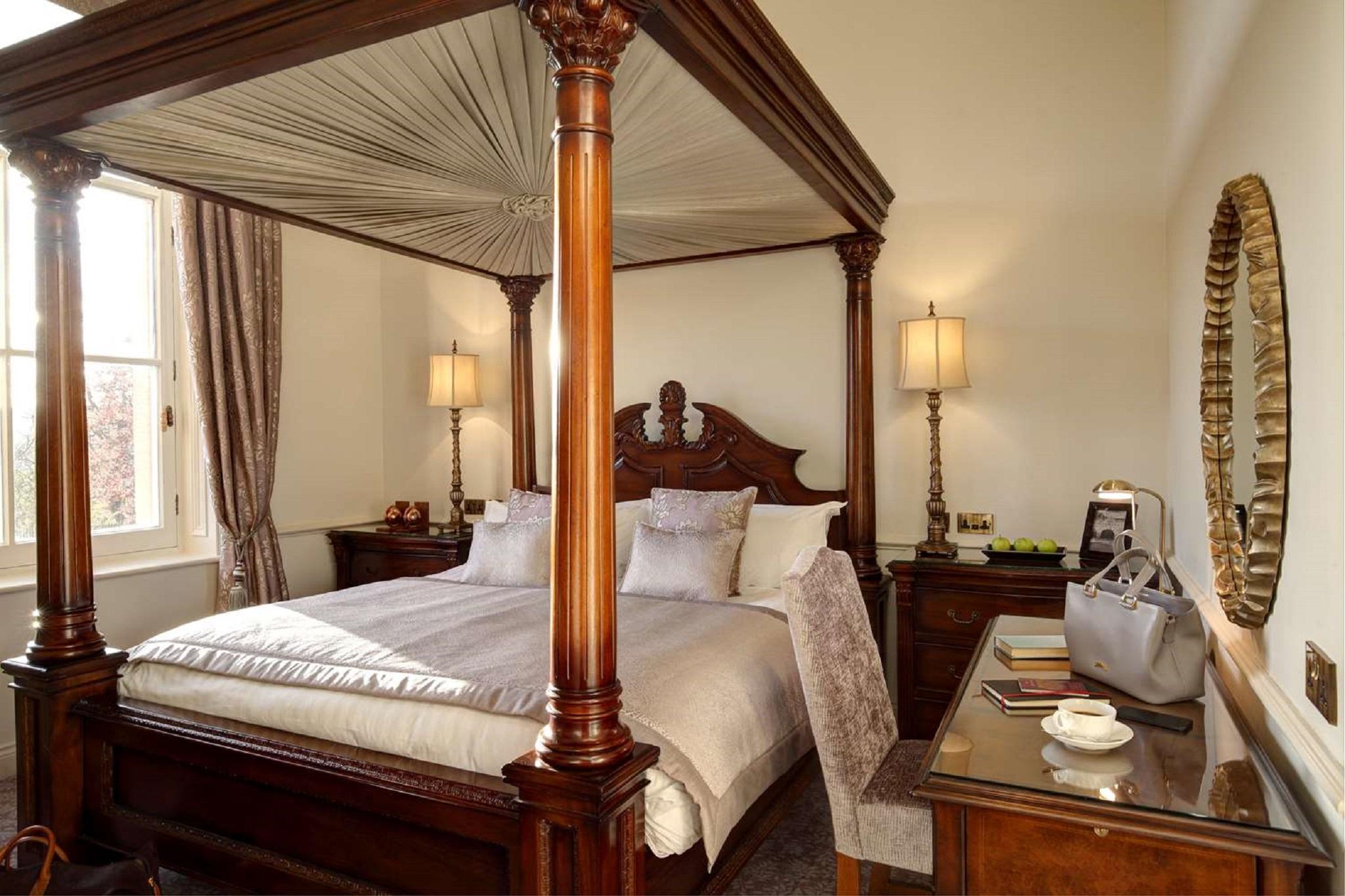 Macdonald Bath Spa Hotel Екстериор снимка The photo shows a beautifully designed bedroom featuring a four-poster bed with a canopy. The bed is adorned with white linens and decorative pillows. On either side of the bed, there are bedside tables with lamps providing warm lighting. Large windo
