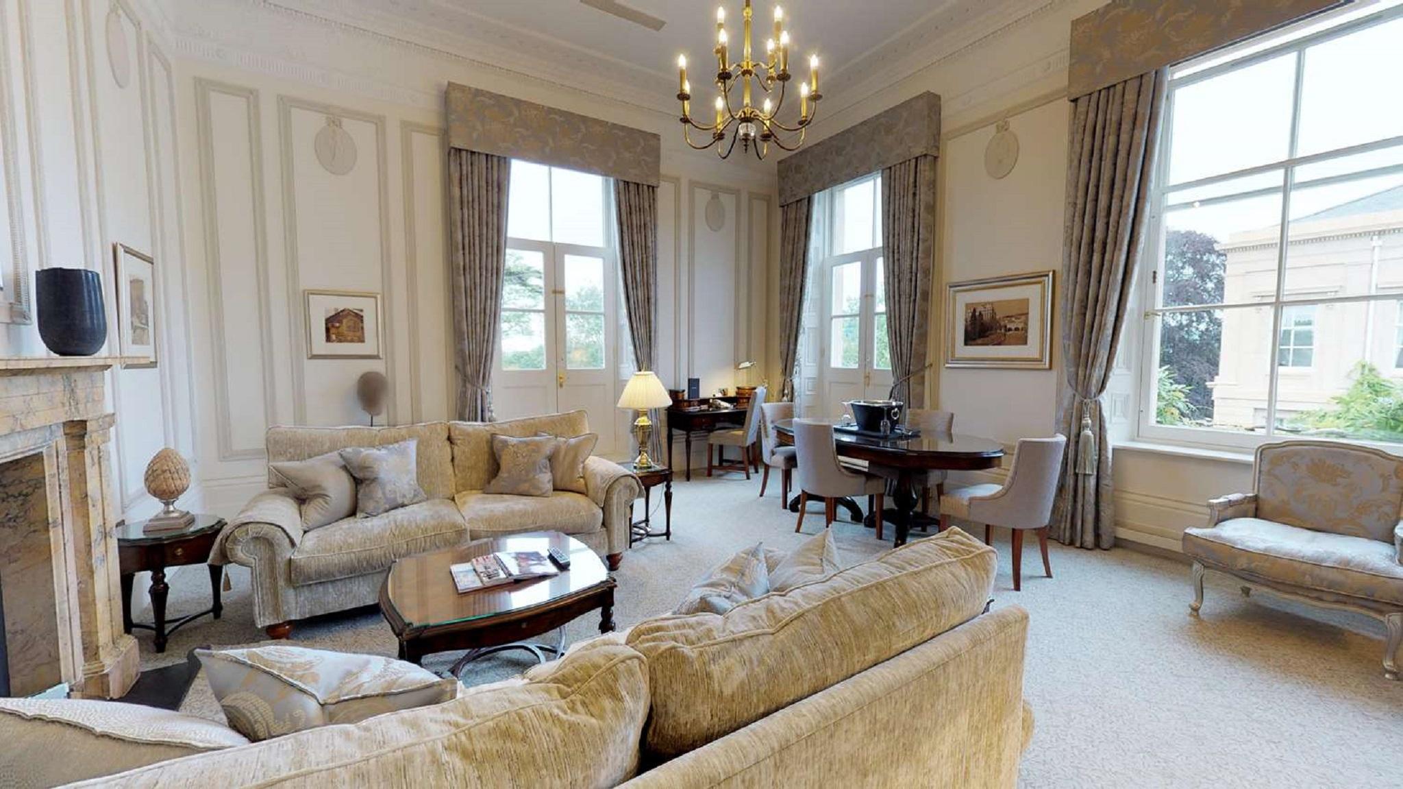 Macdonald Bath Spa Hotel Екстериор снимка The photo displays a spacious and elegantly furnished living room. It features plush sofas and armchairs arranged around a central coffee table, creating a cozy seating area. Large windows adorned with long curtains allow natural light to fill the ro