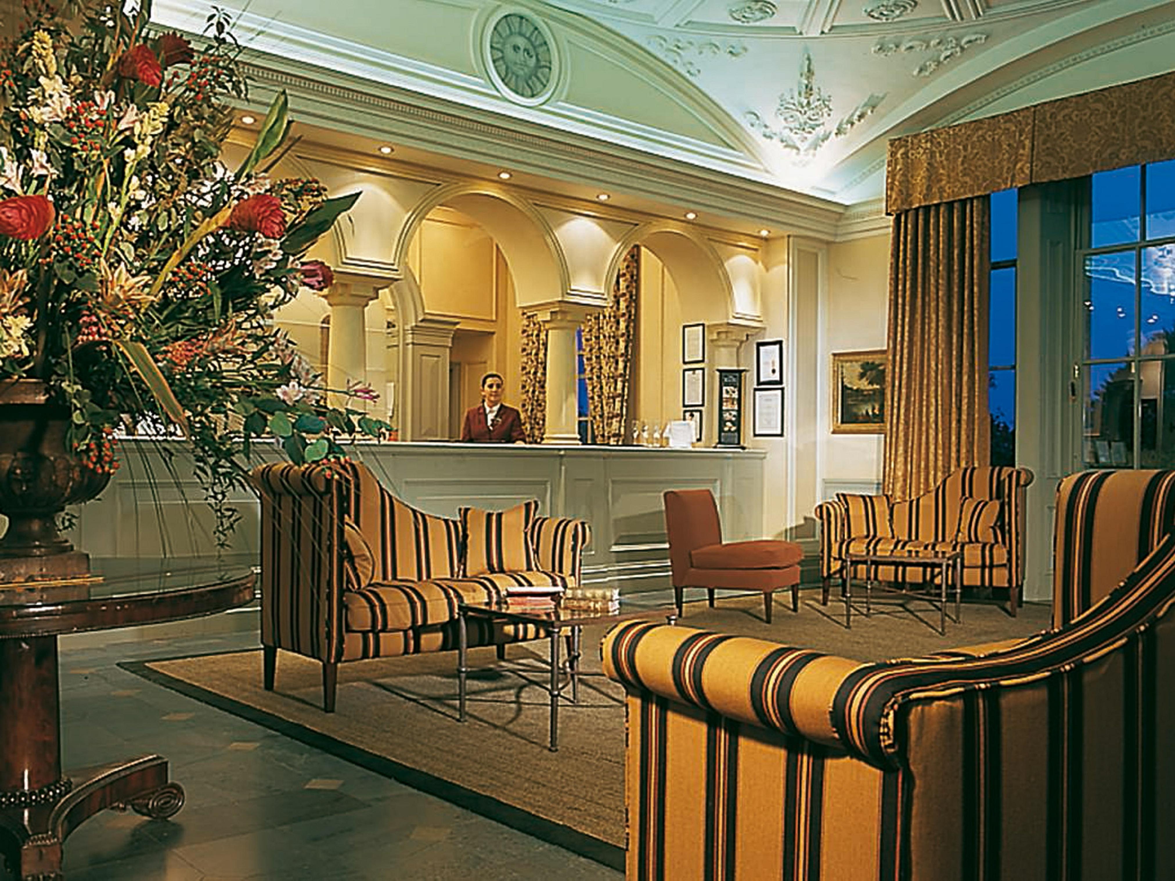 Macdonald Bath Spa Hotel Екстериор снимка The photo shows an elegant hotel lobby. The area features a reception desk with a staff member behind it. Surrounding the reception are comfortable seating arrangements, including striped armchairs and a brown chair. A large vase with an elaborate fl